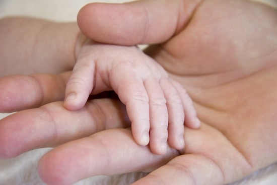 Adulte tenant la main d'un nouveau-né Adulte tenant la main d'un nouveau-né